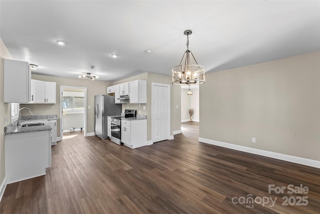 kitchen featuring appliances with stainless steel finishes, a sink, baseboards, white cabinets, and an inviting chandelier