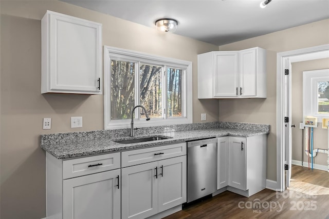 kitchen featuring dark wood finished floors, dishwasher, a sink, light stone counters, and white cabinets