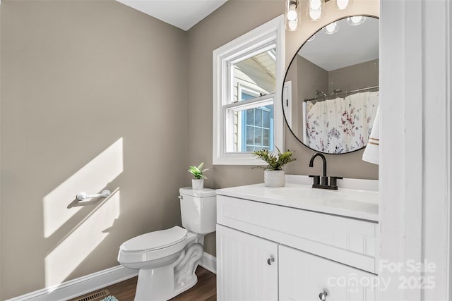 bathroom featuring vanity, toilet, baseboards, wood finished floors, and visible vents
