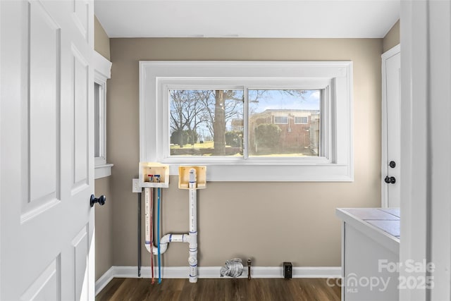 clothes washing area featuring baseboards, laundry area, and dark wood-type flooring