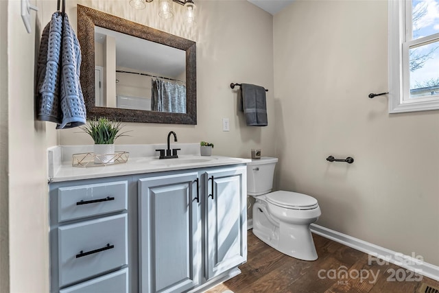 bathroom featuring baseboards, wood finished floors, toilet, and vanity