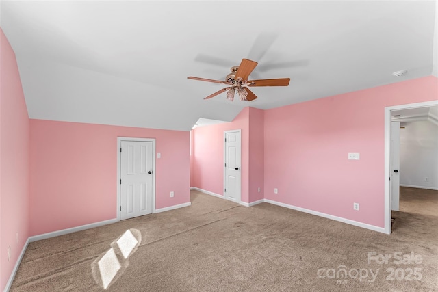 unfurnished bedroom featuring carpet floors, baseboards, a ceiling fan, and vaulted ceiling