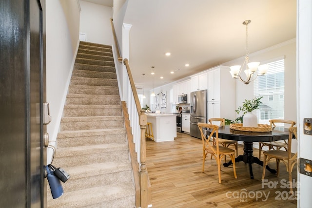 dining area featuring light wood finished floors, ornamental molding, stairs, a chandelier, and recessed lighting