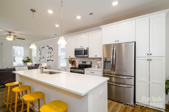 kitchen featuring a kitchen island with sink, a sink, visible vents, open floor plan, and appliances with stainless steel finishes