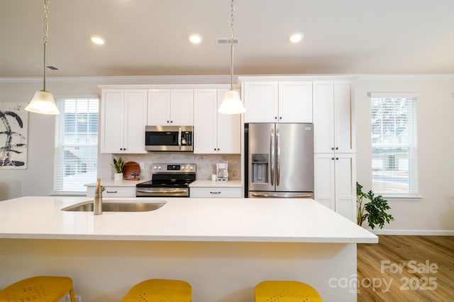 kitchen featuring ornamental molding, stainless steel appliances, a sink, and a kitchen breakfast bar