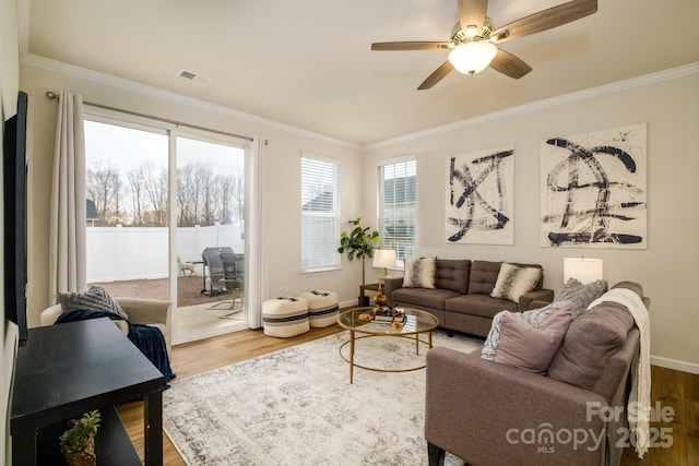 living room featuring ornamental molding, wood finished floors, visible vents, and a ceiling fan