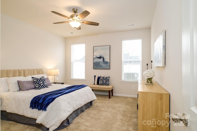 carpeted bedroom featuring a ceiling fan, visible vents, and baseboards