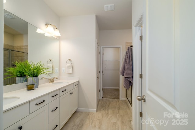 full bathroom featuring a walk in closet, a sink, a shower stall, and double vanity