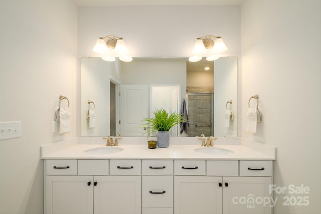 bathroom featuring double vanity, a sink, and a shower stall