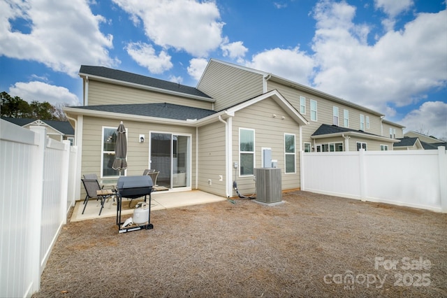 rear view of house with central air condition unit, a patio area, and a fenced backyard