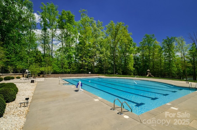 community pool with a patio and fence