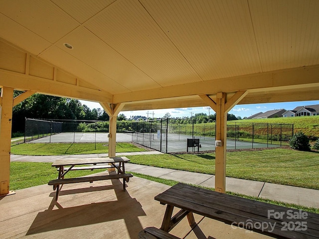 view of property's community with a tennis court, a yard, and fence