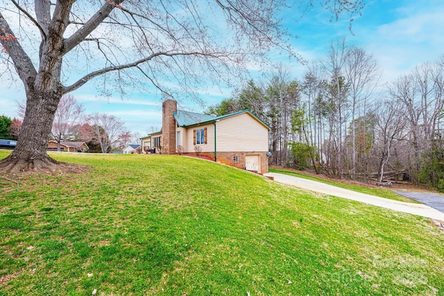 view of side of property featuring a garage, driveway, a chimney, and a yard