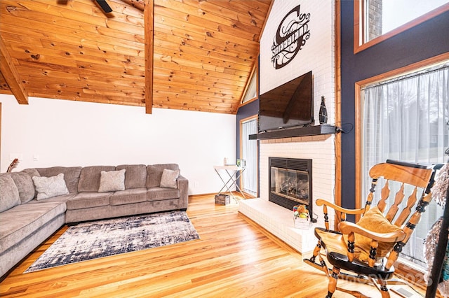 living area with wooden ceiling, a brick fireplace, wood finished floors, and beamed ceiling