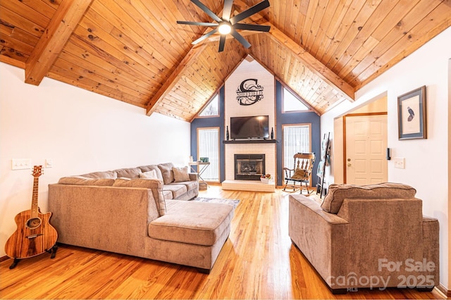 living area featuring beam ceiling, high vaulted ceiling, wooden ceiling, a fireplace, and light wood finished floors