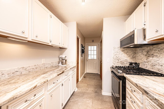 kitchen featuring decorative backsplash, stainless steel microwave, white cabinets, and gas stove