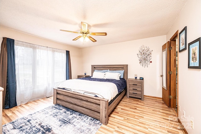 bedroom featuring baseboards, light wood-style floors, ceiling fan, and a textured ceiling