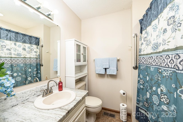 full bath with visible vents, toilet, a textured ceiling, baseboards, and vanity