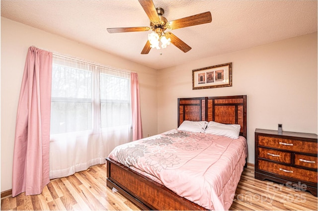 bedroom featuring light wood-type flooring, baseboards, a textured ceiling, and a ceiling fan