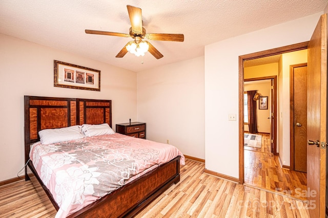 bedroom with ceiling fan, a textured ceiling, light wood-type flooring, and baseboards