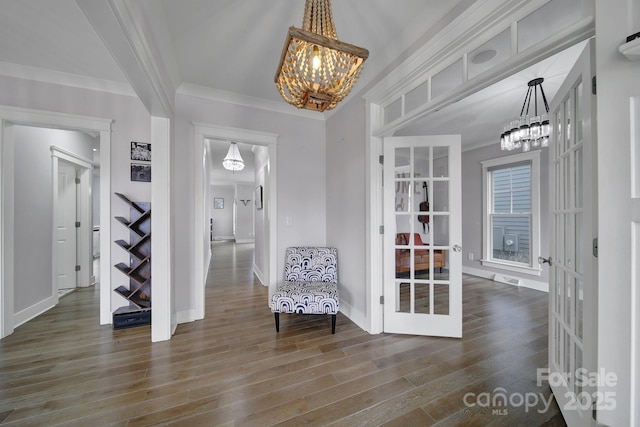 unfurnished room featuring a chandelier, wood finished floors, baseboards, french doors, and ornamental molding