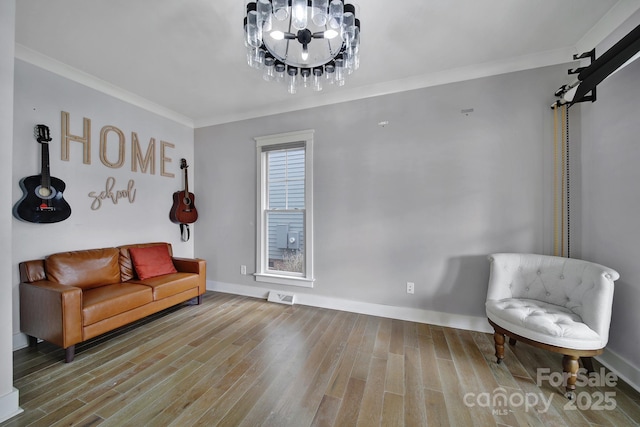 sitting room with visible vents, crown molding, an inviting chandelier, and wood finished floors