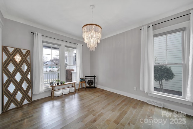 interior space with an inviting chandelier, baseboards, visible vents, and wood finished floors