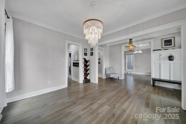 unfurnished dining area featuring baseboards, wood finished floors, and a notable chandelier