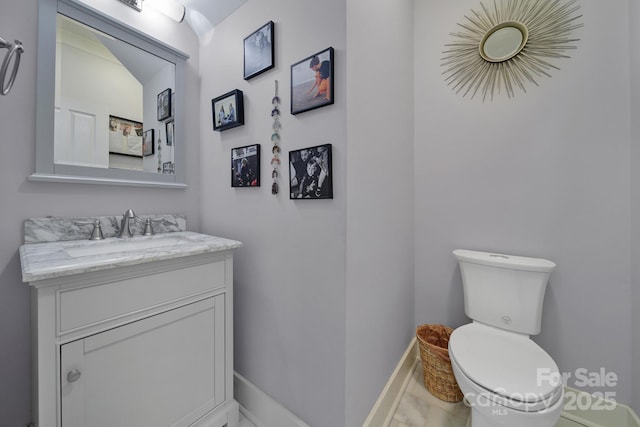 bathroom featuring toilet, baseboards, and vanity