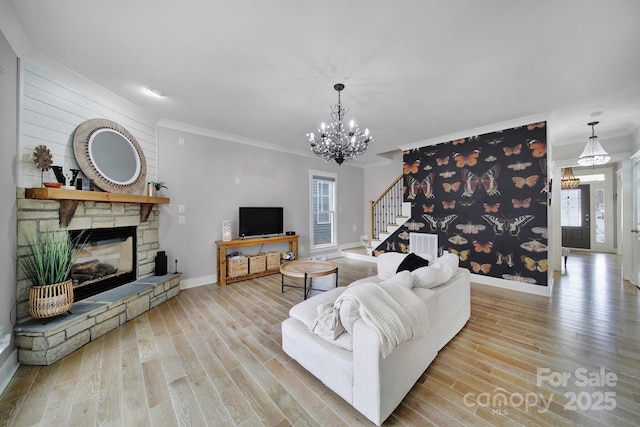 living room featuring a fireplace, wood finished floors, baseboards, stairway, and crown molding