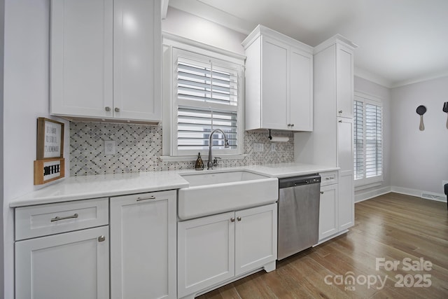 kitchen featuring a wealth of natural light, white cabinets, wood finished floors, stainless steel dishwasher, and a sink