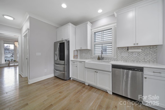 kitchen with a wealth of natural light, appliances with stainless steel finishes, light countertops, and a sink