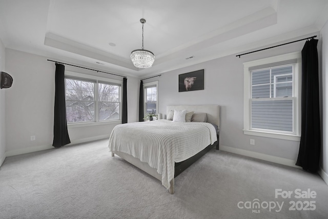 carpeted bedroom featuring a raised ceiling, baseboards, and an inviting chandelier