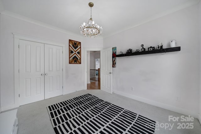 carpeted entrance foyer with crown molding, baseboards, and an inviting chandelier