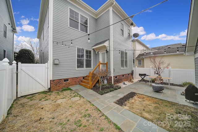 back of property with a gate, a patio area, a fenced backyard, and crawl space