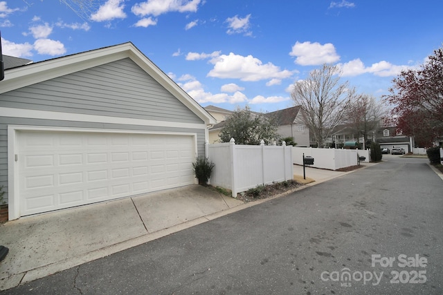 garage featuring driveway and fence