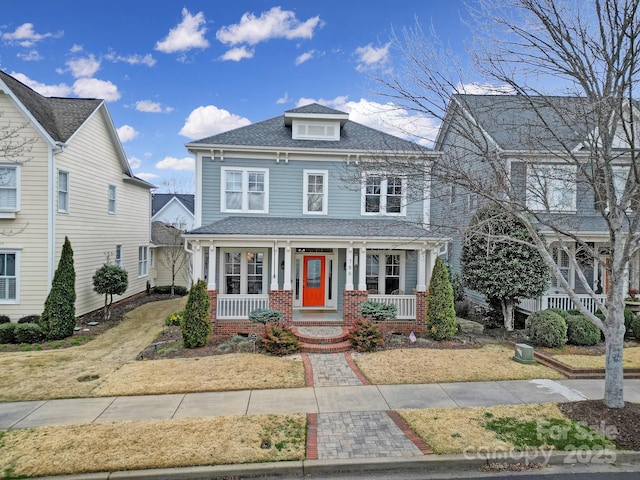 american foursquare style home with a porch and roof with shingles