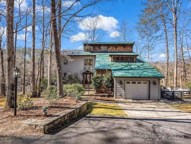 view of front facade featuring a garage, driveway, and metal roof