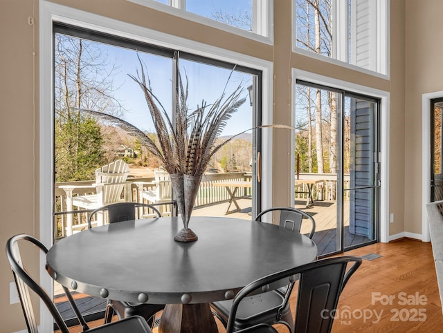 dining area featuring a high ceiling, baseboards, and wood finished floors