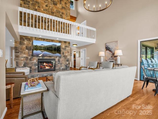 living room with a chandelier, a stone fireplace, plenty of natural light, and wood finished floors