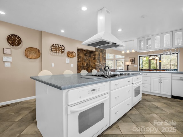 kitchen with island exhaust hood, a center island, white appliances, white cabinets, and glass insert cabinets