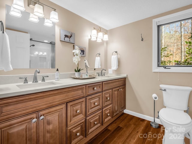 bathroom with toilet, wood finished floors, baseboards, and a sink