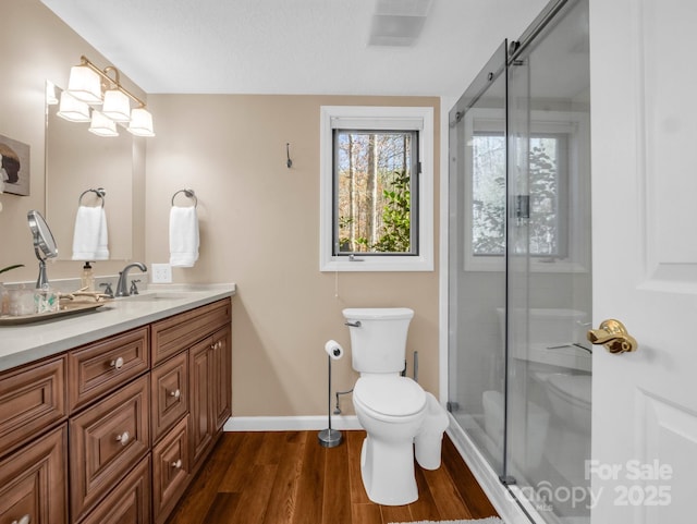 full bath featuring a shower stall, toilet, vanity, and wood finished floors