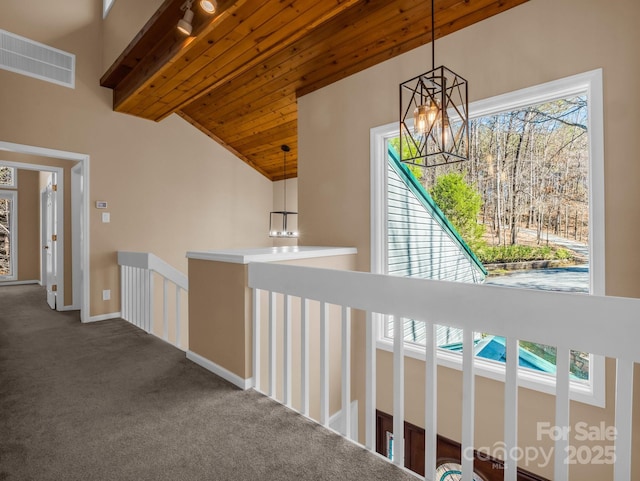 hallway with visible vents, an inviting chandelier, wooden ceiling, carpet flooring, and baseboards