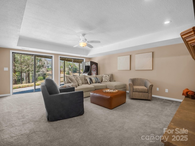 living room with baseboards, a raised ceiling, a textured ceiling, and carpet floors