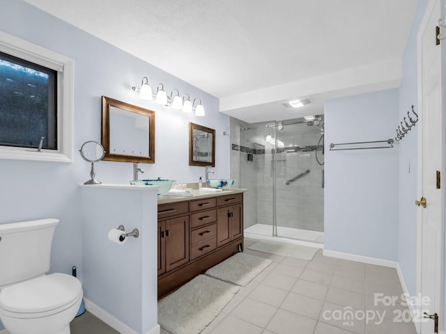 full bath with baseboards, double vanity, a stall shower, a sink, and toilet