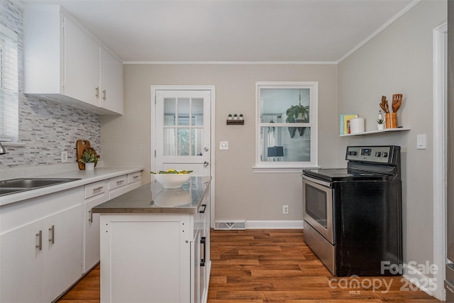 kitchen featuring wood finished floors, visible vents, stainless steel electric range, a sink, and white cabinets