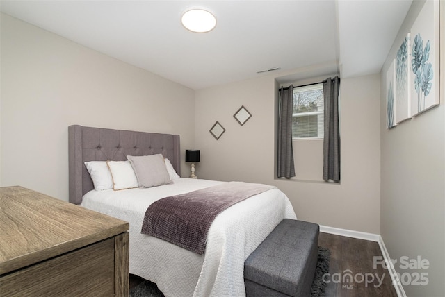 bedroom featuring visible vents, baseboards, and wood finished floors