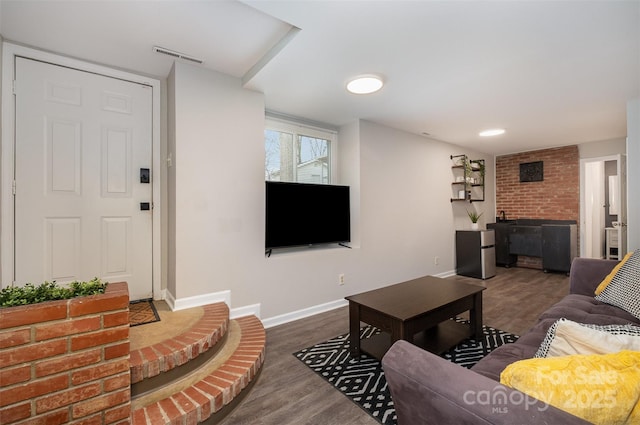 living area featuring visible vents, baseboards, and wood finished floors