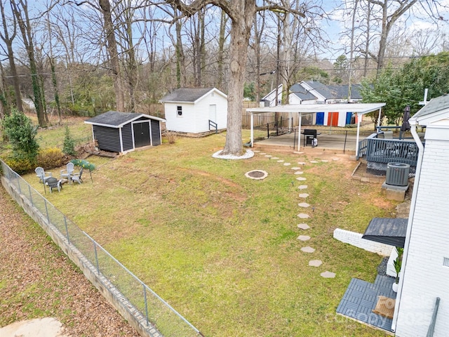 view of yard with a detached carport, fence, an outdoor fire pit, a storage shed, and an outbuilding